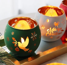 Load image into Gallery viewer, Green and white frosted glass tealight holders with gold dove and Merry Christmas designs glowing warmly.