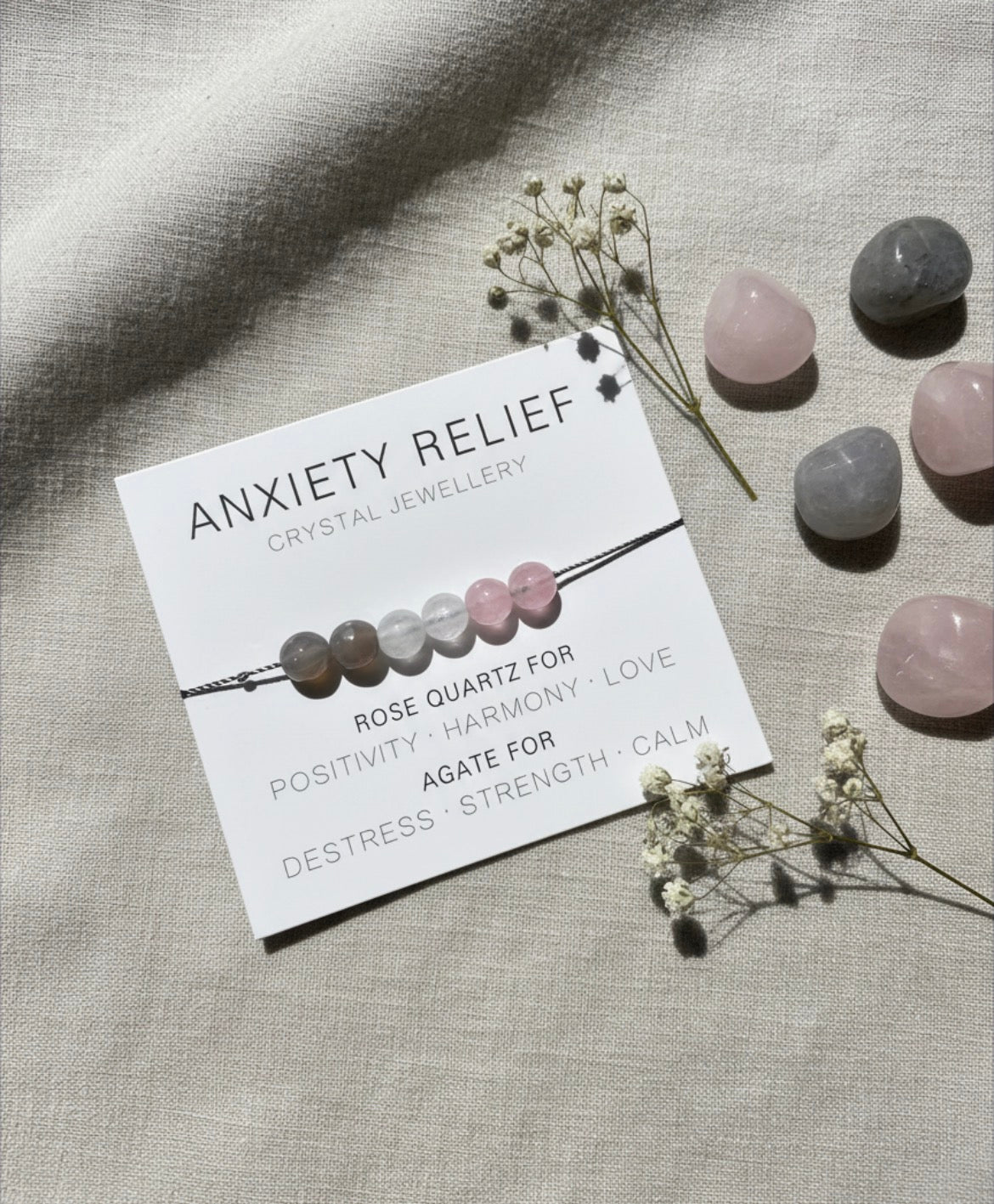 Anxiety relief crystal bracelet with rose quartz and agate displayed on branded card in minimalist neutral setting