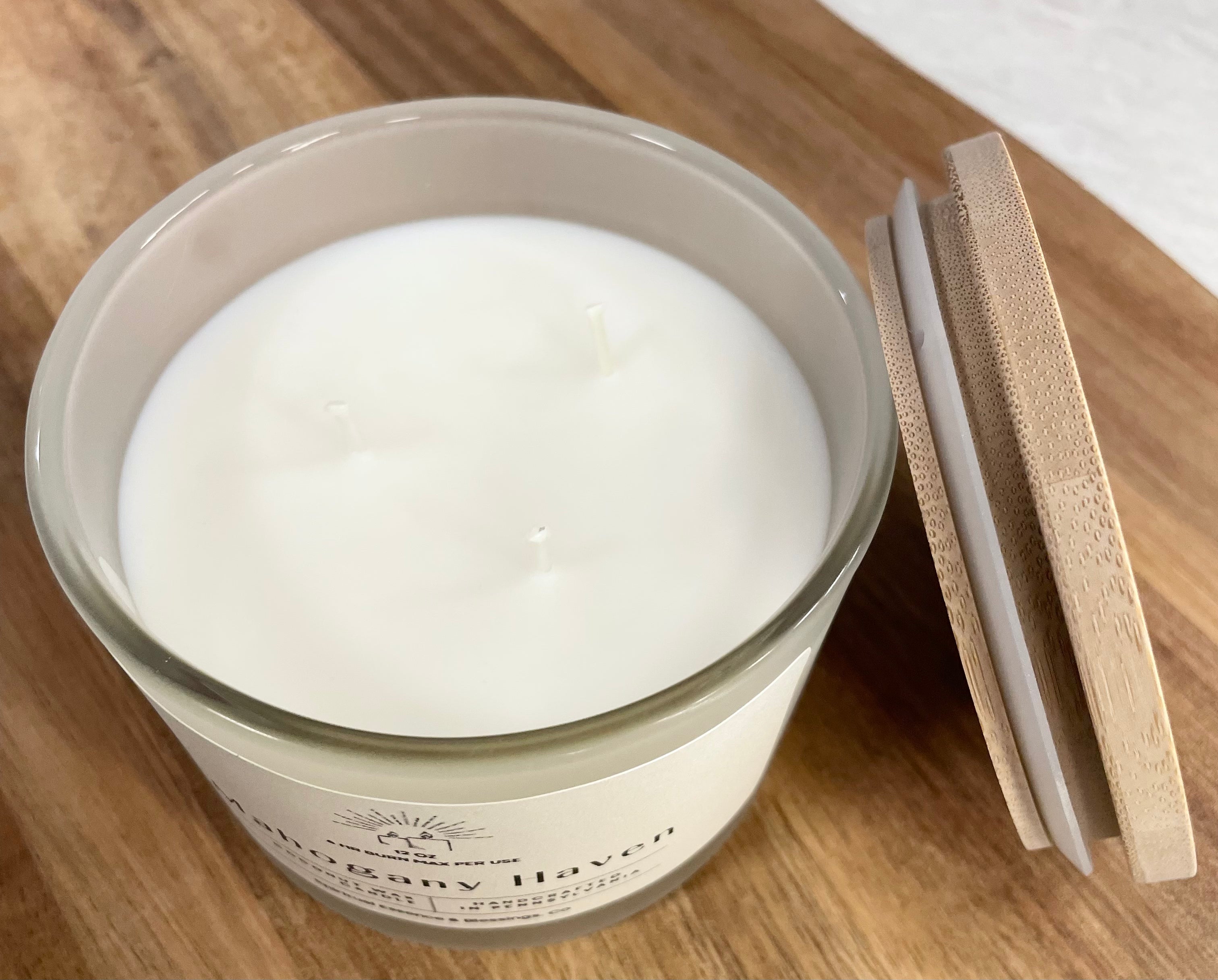 Mahogany Haven triple-wick candle open with bamboo lid beside it — clean coconut wax surface